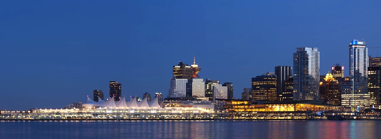 Vancouver waterfront buildings and the white sail-shaped roof of Canada Place at dusk